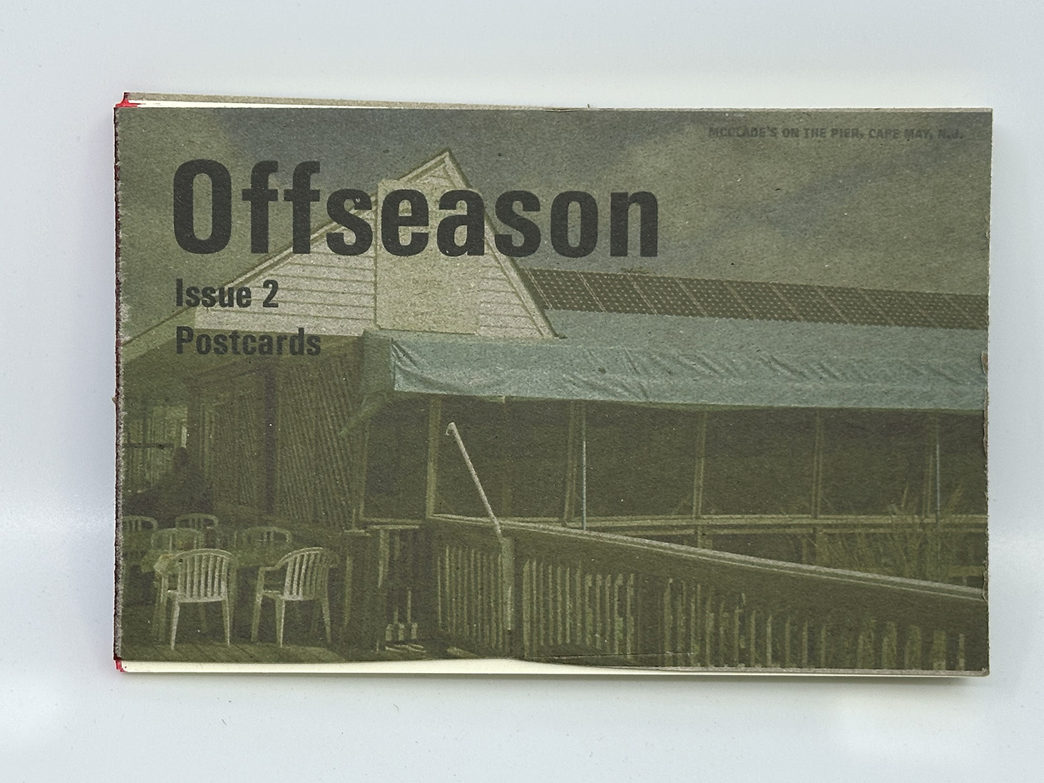 photograph of a zine with the title Offseason Issue 2 Postcards over a postcard showing a restaurant on the beach